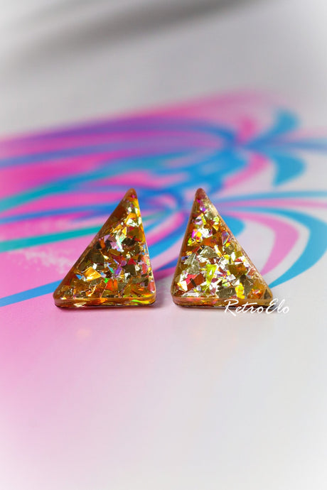 Triangular glittery earrings on a colorful abstract background
